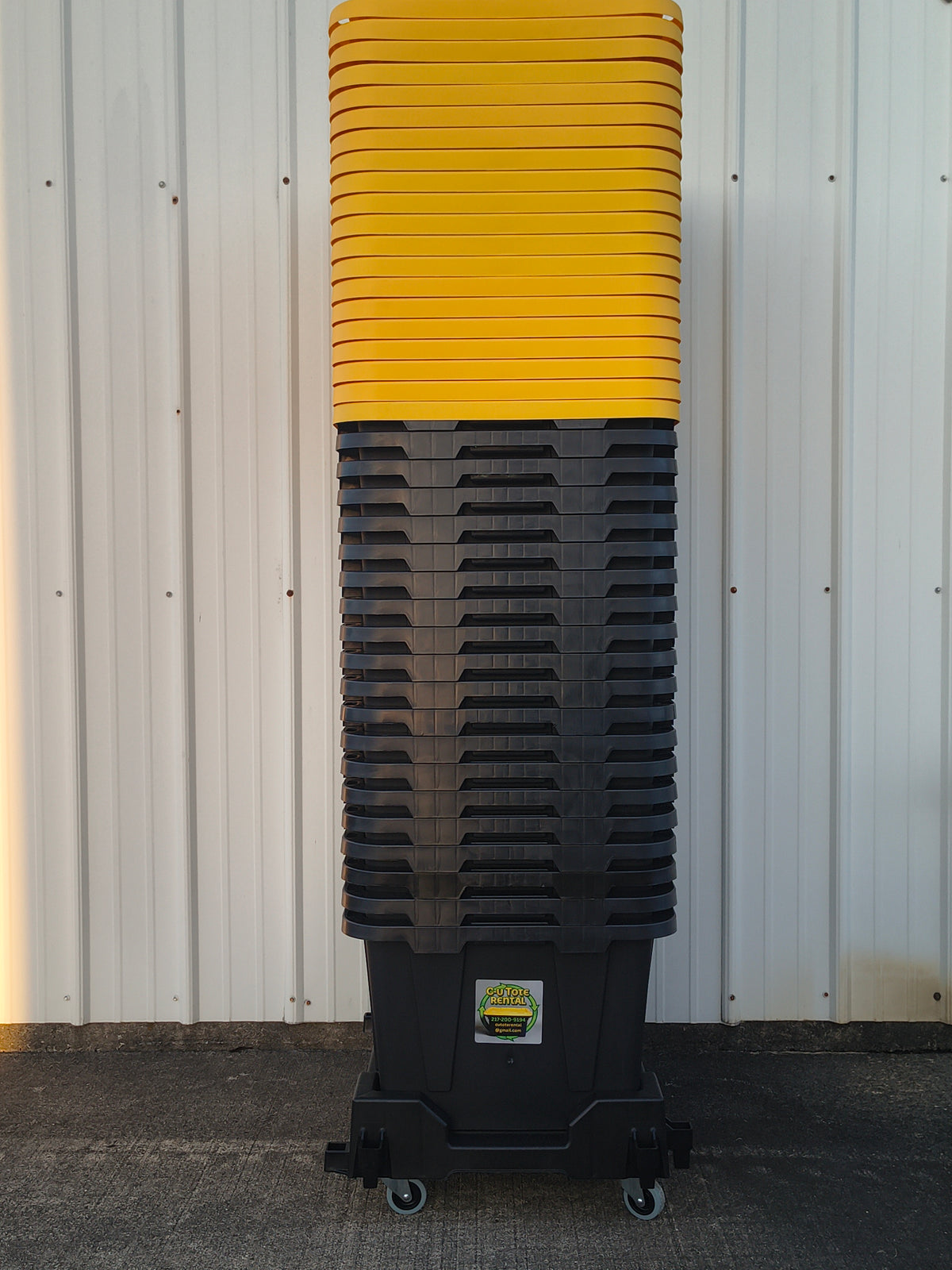 Stack of black totes with yellow lids on dolly